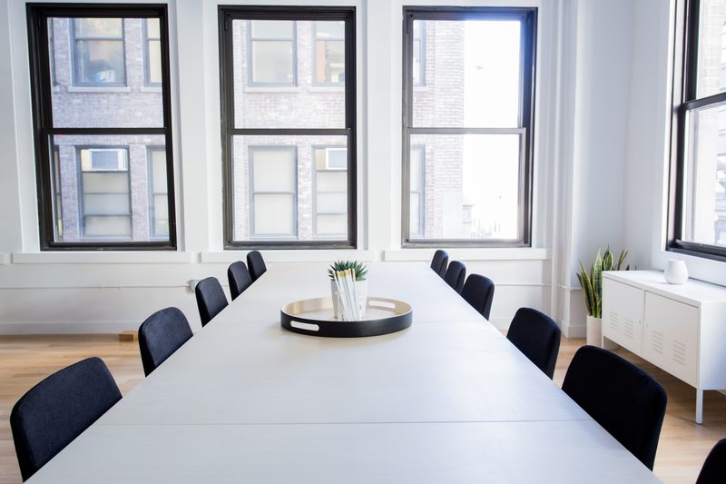 A bright, minimal meeting room with a long table and chairs.